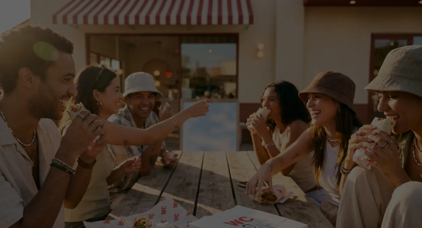 Friends sharing Wrap City sandwiches at a table