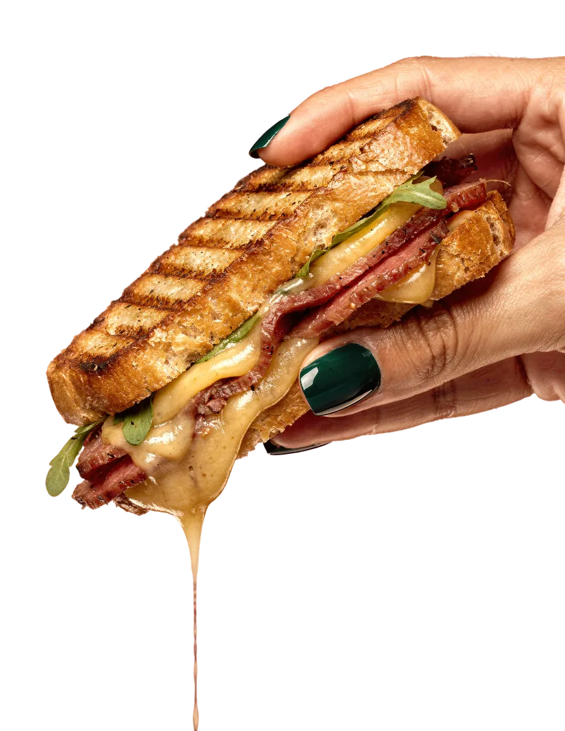 A hand holding a toasted Wrap City sandwich, cheese pulling