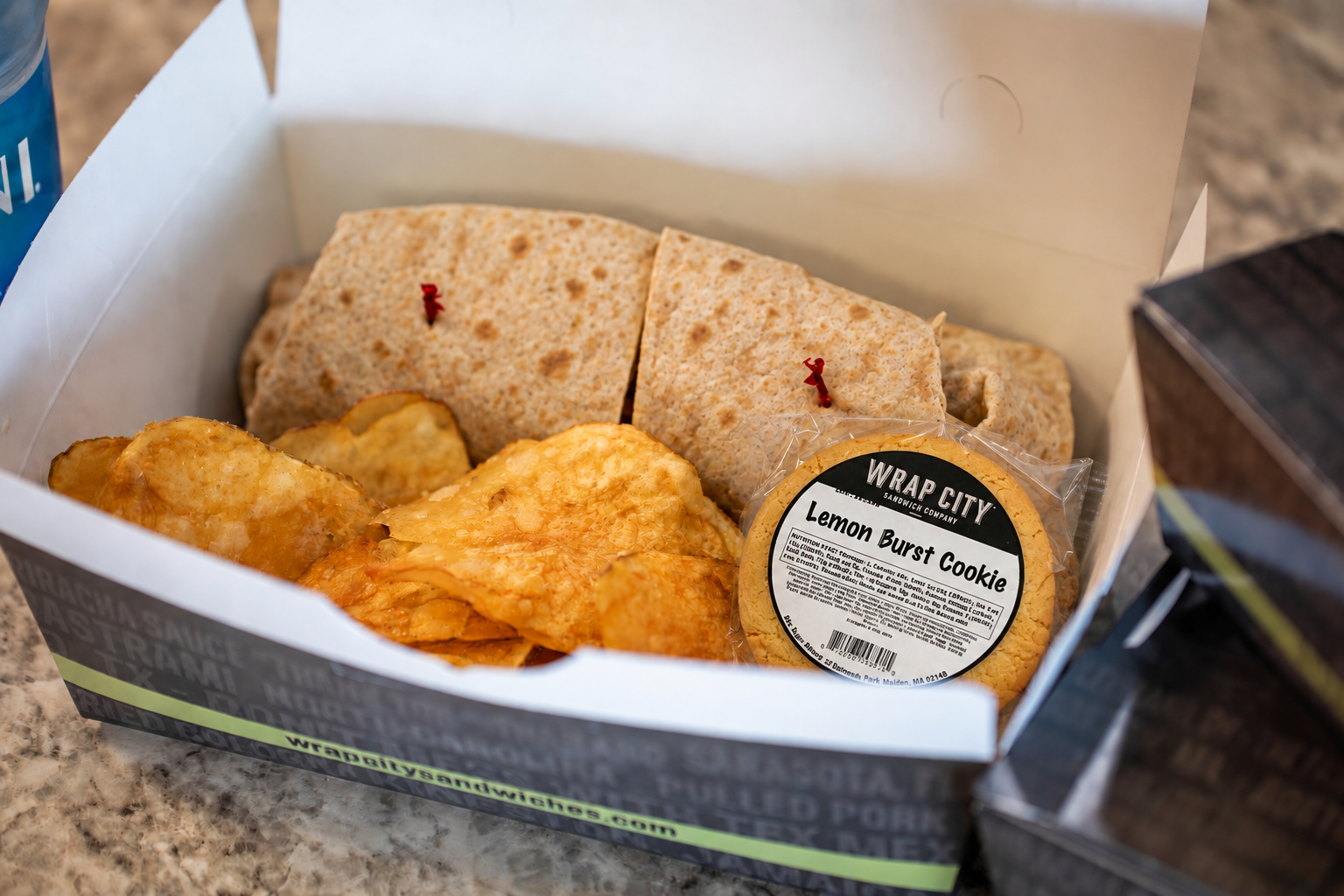 A Wrap City box lunch with a grilled sandwich, chips and a cookie
